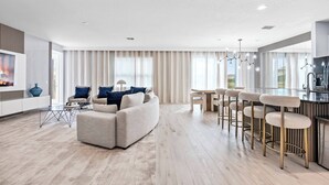 Ett modernt vardagsrum med en soffa, ett soffbord och en bardisk med barstolar.