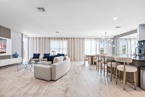 Ein modernes Wohnzimmer mit einer Couch, einem Couchtisch und einer Bar mit Hockern.