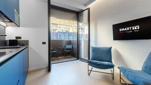 Eine moderne Küche mit Essbereich, einer Schiebeglasdoor zum Balkon und einem Wand-Fernseher, der 'SMART TV' mit Logos zeigt.