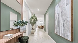 Ein Korridor mit einer hölzernen Bank, einem Blumentopf und einem großen abstrakten Gemälde an der Wand.