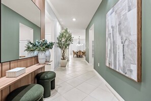 A hallway with a wooden bench, a potted plant, and a large abstract painting on the wall. - 10BR house sleeps 23 with game room (Clermont)