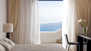 A hotel room with a bed, a desk, a chair, and a view of the sea. - Magnificent Santorini Villa | Villa Aphrodite’s Dream | 2 Bedrooms |. (Santorini)