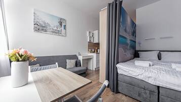 A modern hotel room with a bed, a desk, and a small kitchenette.