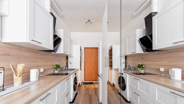 Een moderne keuken met witte kasten, houten vloeren en een centraal eiland.