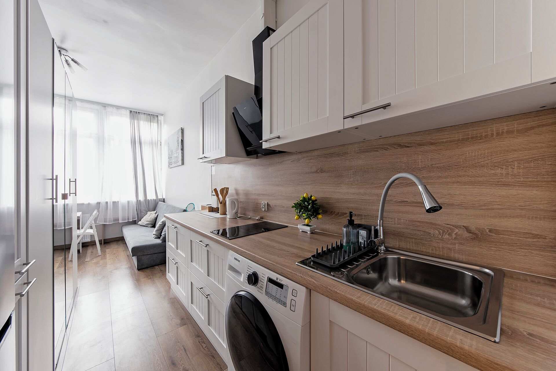 Una cocina moderna con lavadora y secadora integradas, un salpicadero de madera y un lavamanos grande.