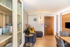 Ein modernes Interieur mit einer Couch, einem Esstisch und Regalen mit Tassen und Gläsern.