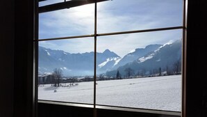 Une fenêtre donnant sur des montagnes enneigées et un ciel dégagé.