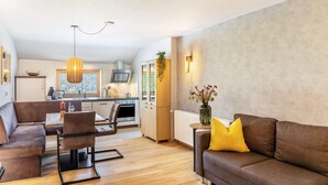 Un salon moderne avec un canapé, une table à manger, des chaises et une cuisine en arrière-plan.