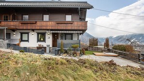 Une maison à deux étages avec un balcon, un mur en pierre et une vue sur les montagnes.