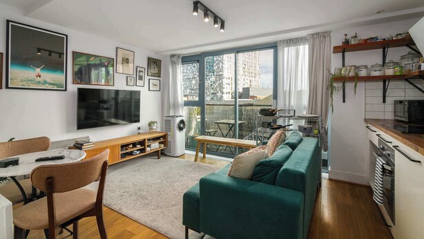 A living room with a TV, sofa, dining table, and kitchen area with a window. - Charming Central Studio with Balcony in Birmingham (West Midlands)