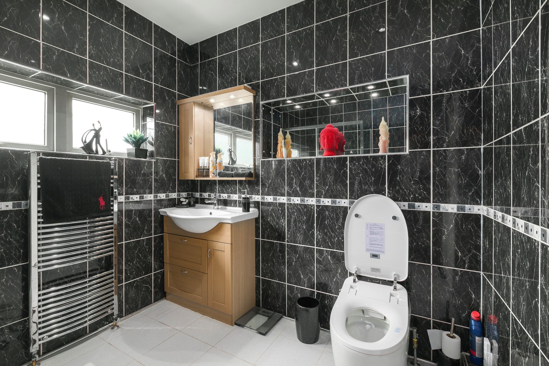 Une salle de bain moderne avec un mur recouvert de marbre noir, un lavabo blanc et des toilettes.
