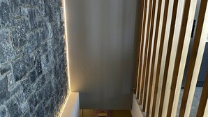 Een trap met een marmeren muur aan één kant en een houten leuning aan de andere kant.