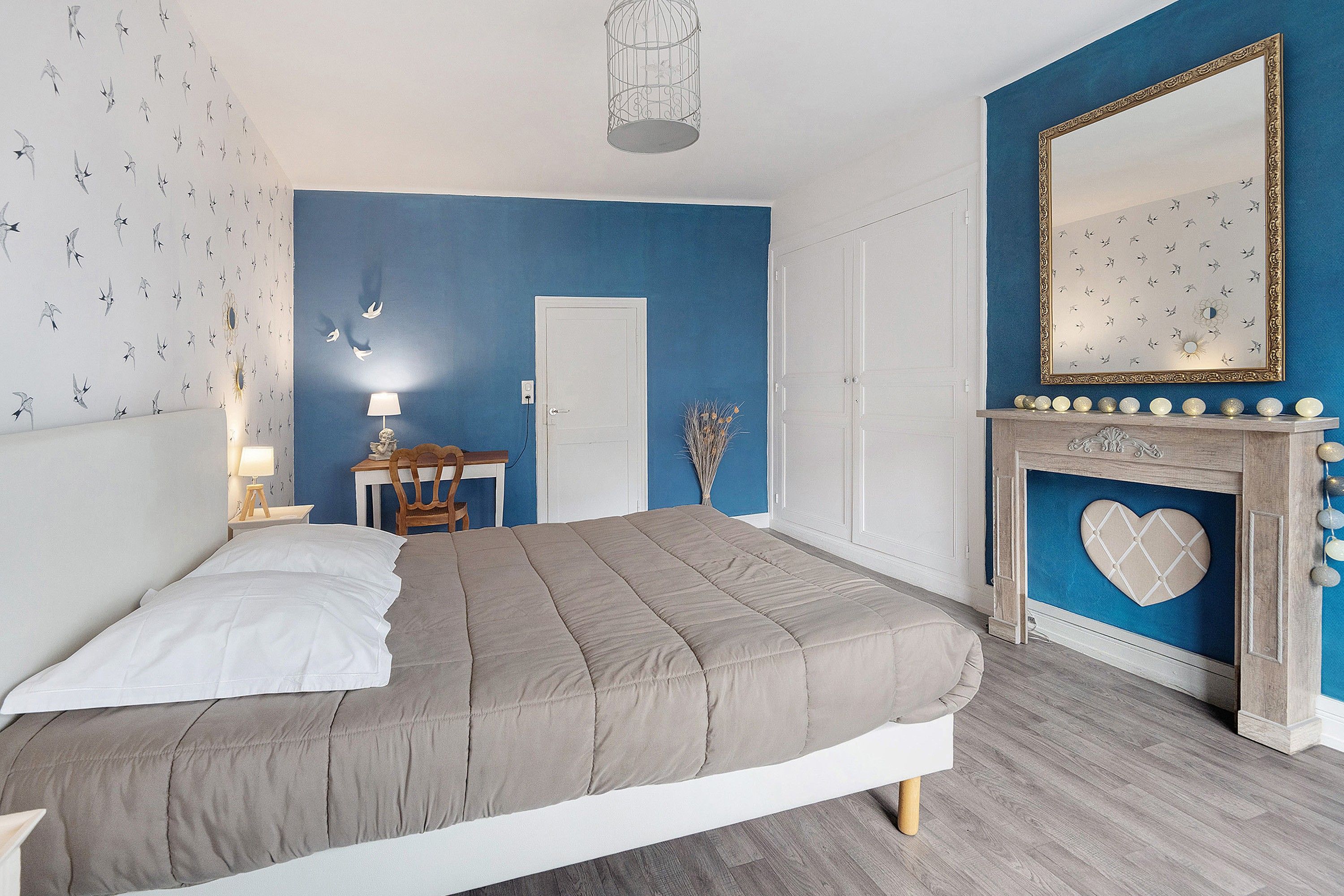 A bedroom with a bed, a dresser, a mirror, and a fireplace.