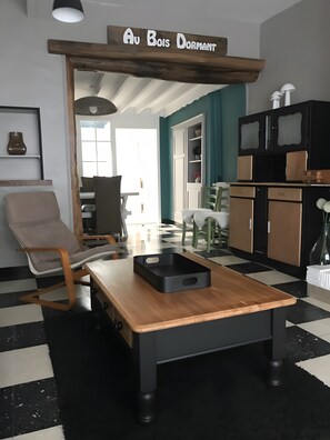 Un salon moderne avec une table basse en bois, un canapé et un coin repas avec des chaises.