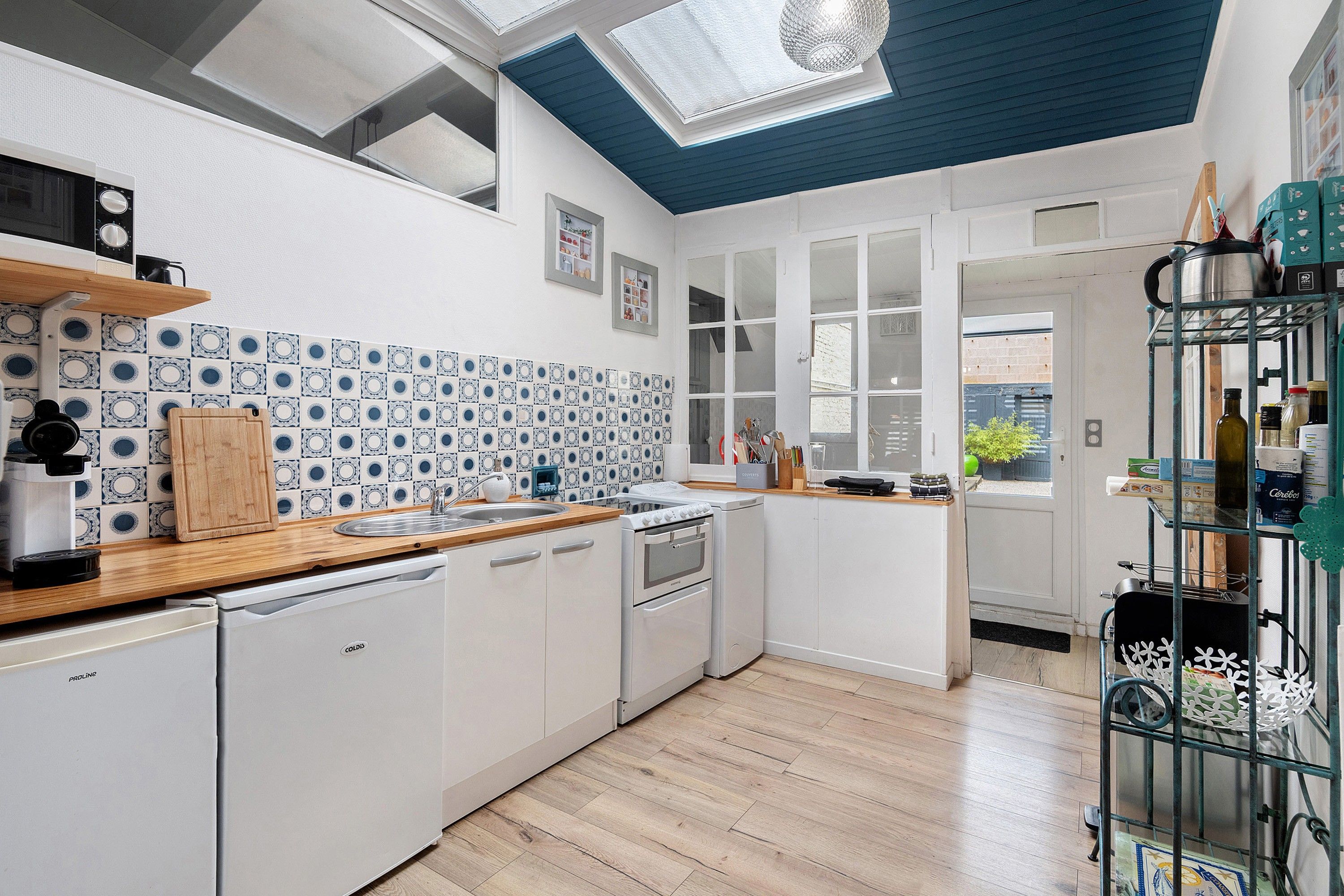 A compact kitchen with white cabinets, a wooden countertop, and a tiled backsplash.