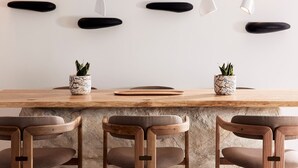 Un comedor moderno con una mesa de madera, tres sillas y lámparas colgantes.