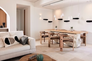 Ein modernes Wohnzimmer mit einer Couch, einem Couchtisch und einem Essbereich mit Stühlen und einem Holztisch.
