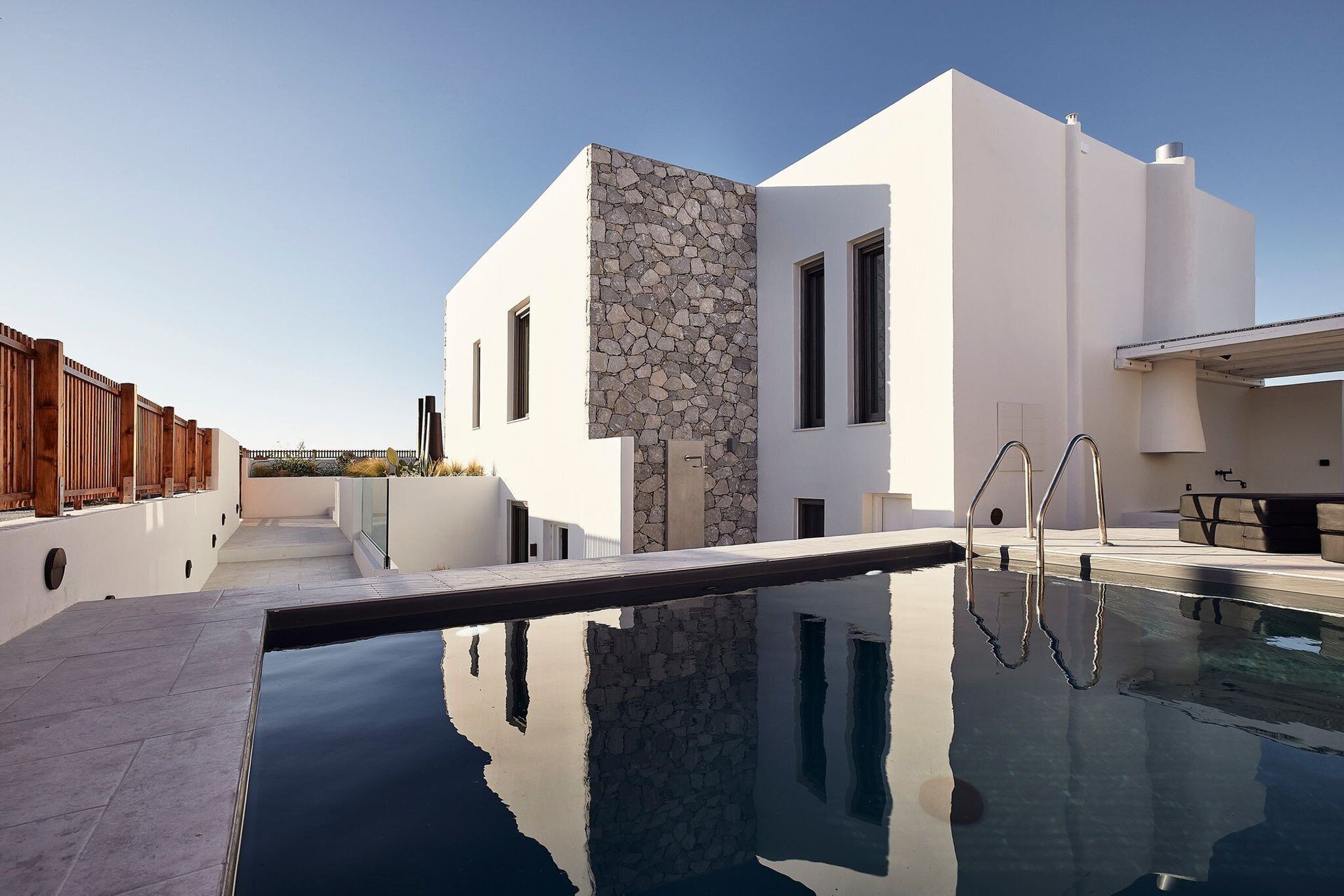A modern building with a stone facade, a swimming pool, and a wooden deck.