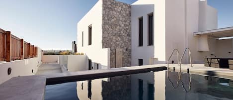 A modern building with a stone facade, a swimming pool, and a wooden deck.