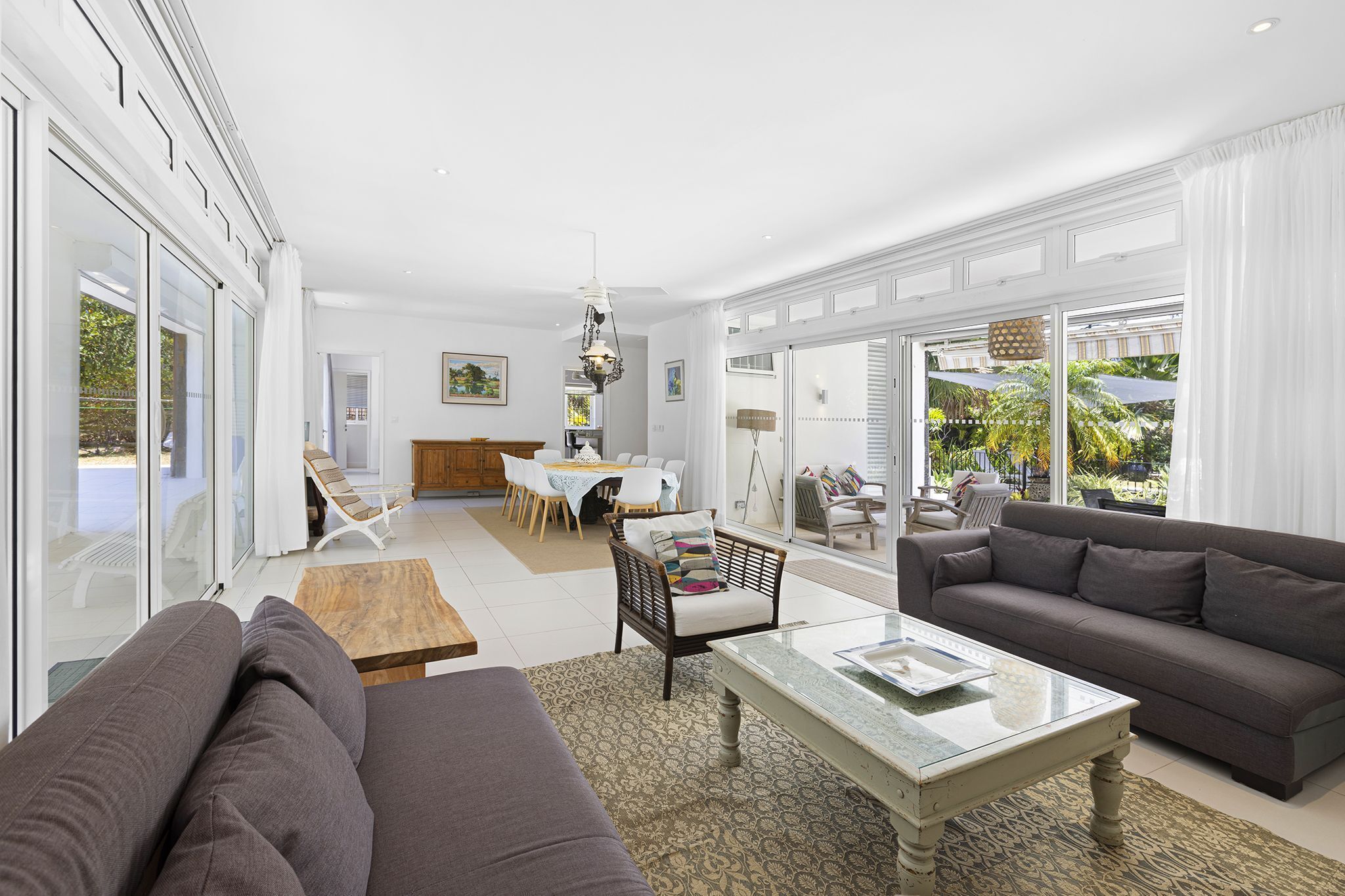 A spacious living area with a sofa, a coffee table, and a dining table set with chairs.