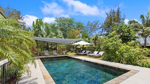 A rectangular swimming pool with clear blue water, surrounded by a tiled deck and lush tropical vegetation. - Croix Du Sud (Trou d'Eau Douce)