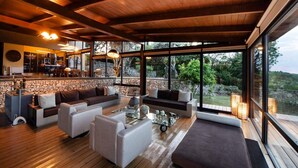 Amplia sala de estar con pared de piedra, ventanas grandes y techo de madera.