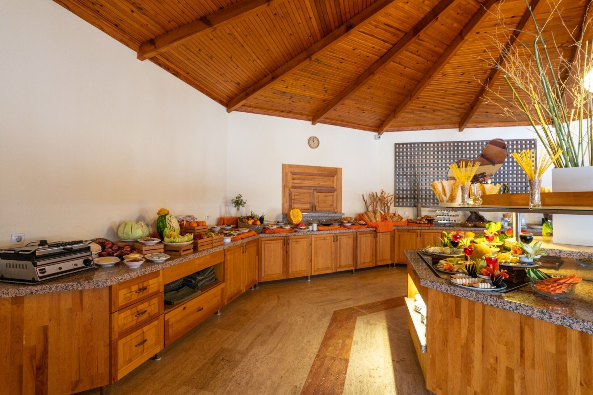 Une cuisine avec des meubles en bois, un plan de travail en granit et une variété d’aliments exposés.