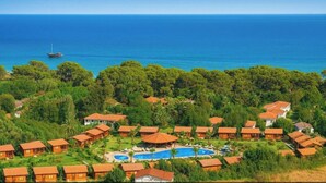 Une station balnéaire dotée de plusieurs hébergements de type bungalow, d’une piscine centrale et offrant une vue sur la mer.