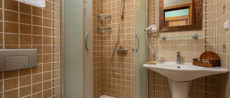 A bathroom with a glass-enclosed shower, a sink with a mirror above it, and a towel hanging on the wall.