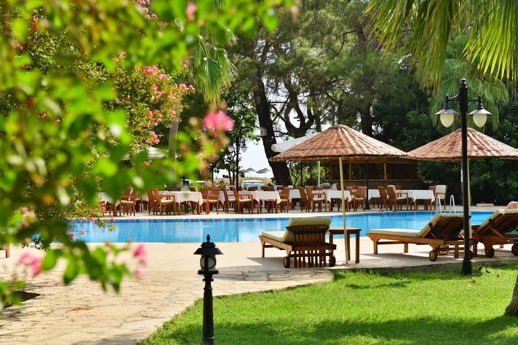 A poolside area with lounge chairs, tables, and umbrellas.