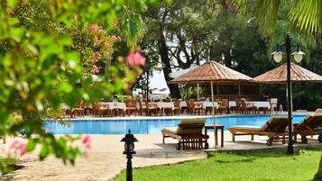 A poolside area with lounge chairs, tables, and umbrellas.