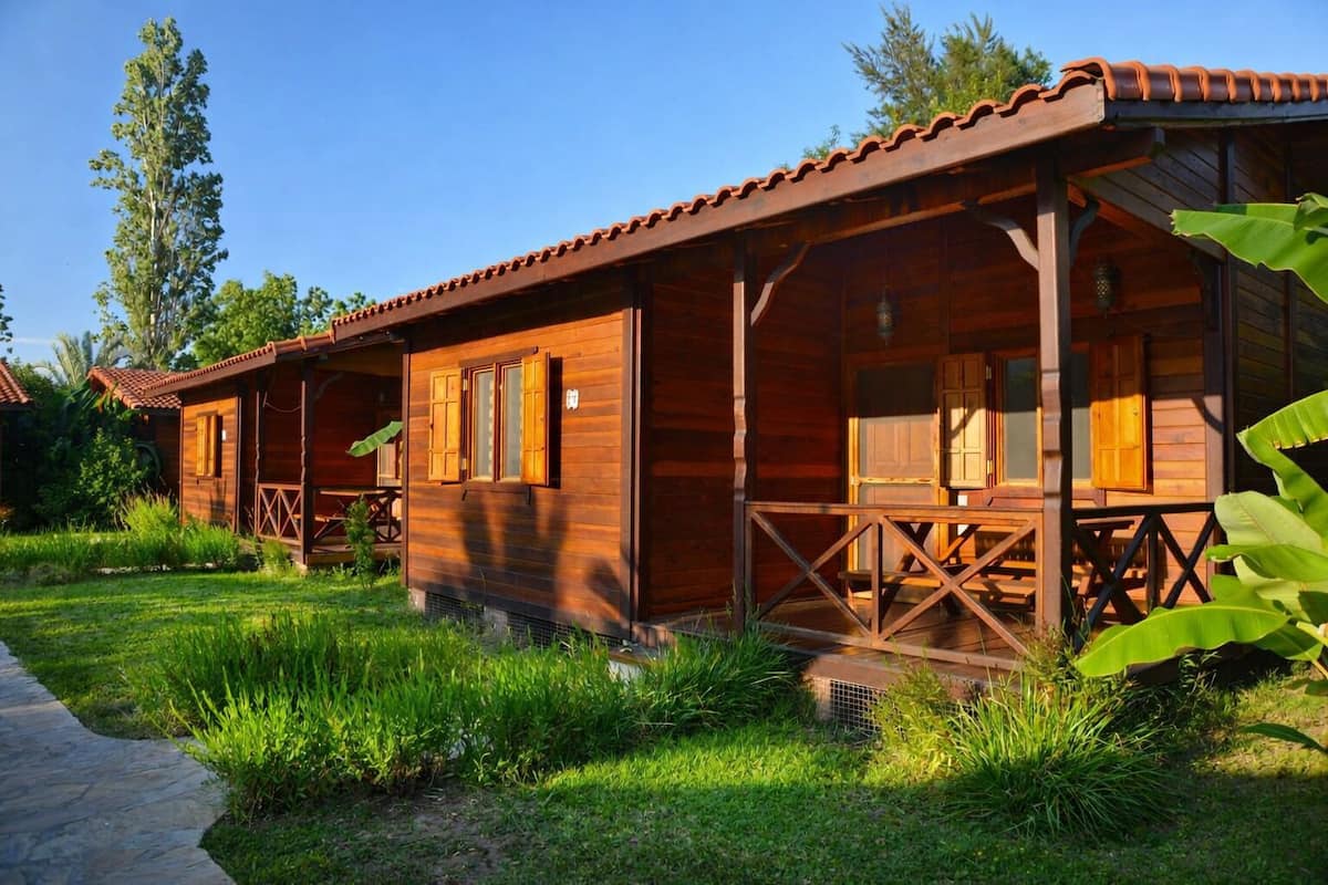Eine Holzhütte mit Veranda, umgeben von üppigem Grün.