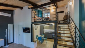 Eine moderne Loft-Wohnung mit einer Holztreppe, einem Essbereich mit blauen Stühlen und einer Küche mit Einbauofen.
