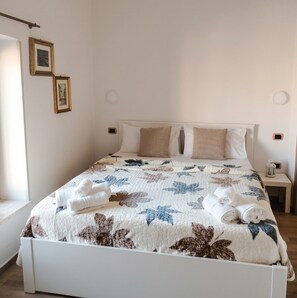 A neatly made bed with a floral quilt, white pillows, and rolled towels. - Casicarillo 800 - Appartamento Contemporaneo (Sala)