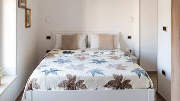 A bed with a floral bedspread, a bedside table, and a wall-mounted light fixture.