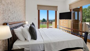 Une chambre d’hôtel avec un lit, une télévision, une armoire en bois et un balcon avec vue.