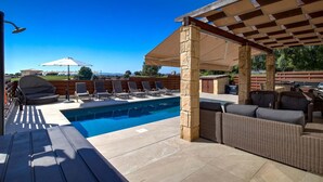 Un espace extérieur avec une piscine, des chaises longues, une pergola et un coin salon abrité.
