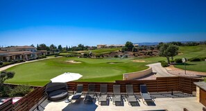 A golf course with a clubhouse, outdoor seating area with lounge chairs, and a clear view of the landscape. - Villa HG08 Pyrinas - Three Bedroom Villa, Sleeps 6 (Kouklia)