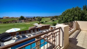 A poolside area with lounge chairs and a view of a golf course.
