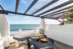 Una terraza con una mesa preparada para comer, con vistas al mar.