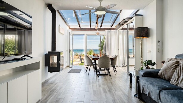 A modern kitchen with a dining area, a ceiling fan, and a view of the sea. - Modern holiday home by beach in Calahonda (Málaga)