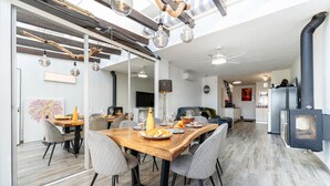 A modern kitchen with a central island, a dining area with a wooden table, and a built-in wood stove. - Modern holiday home by beach in Calahonda (Málaga)
