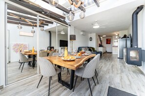 A modern kitchen with a central island, a dining area with a wooden table, and a built-in wood stove. - Modern holiday home by beach in Calahonda (Málaga)
