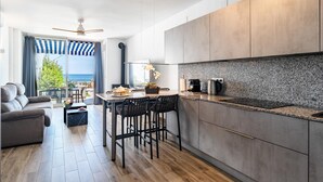 A modern kitchen with a granite countertop, a coffee machine, and a dining area with bar stools. - Beachfront holiday home in Malaga (Malaga)