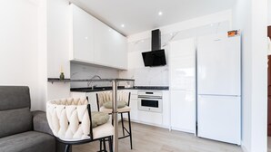 Eine moderne Küche mit weißen Schränken, einer schwarzen Dunstabzugshaube und einem weißen Kühlschrank.