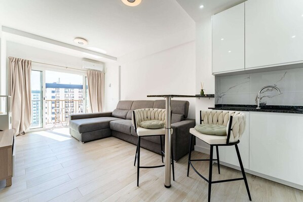 Een modern appartement met een eetgedeelte, keuken en balkon met uitzicht op gebouwen.