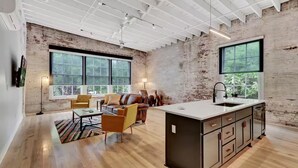 A spacious kitchen with a large island, a dining area with a sofa and chairs, and large windows providing natural light. - The Majestic 1BR 203-Walking distance to downtown Hot Springs & 6 min to Oaklawn (Hot Springs)