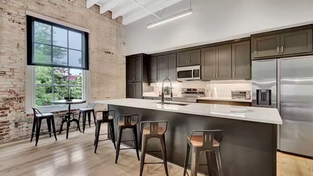 A modern kitchen with dark cabinets, stainless steel appliances, and a large island with bar stools. - The Majestic 1BR 203-Walking distance to downtown Hot Springs & 6 min to Oaklawn (Hot Springs)