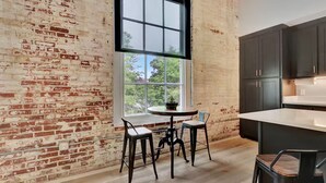 A kitchen with a brick wall, a large window, and dark cabinets. - The Majestic 1BR 203-Walking distance to downtown Hot Springs & 6 min to Oaklawn (Hot Springs)
