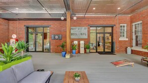 An indoor space with brick walls, a sign reading "Fraser Smith to Beer and Wine," and various seating areas with plants. - The Majestic 1BR 203-Walking distance to downtown Hot Springs & 6 min to Oaklawn (Hot Springs)